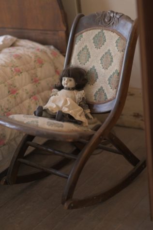 Photo of a doll in a rocking chair. 