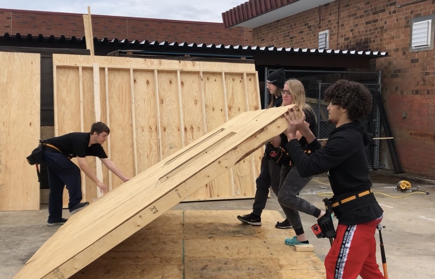 Four+Construction+students+propping+up+the+first+wall+of+a+shed+for+class.